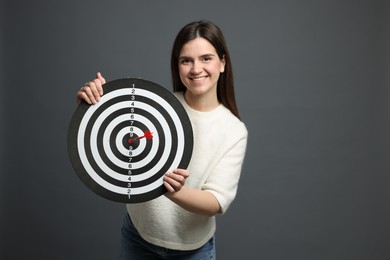 Photo of Targeting. Smiling woman with dart board and arrow on grey background
