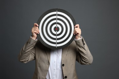Photo of Targeting. Businesswoman hiding behind dart board on grey background