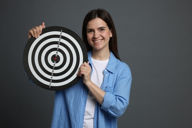Photo of Targeting. Smiling woman with dart board on grey background