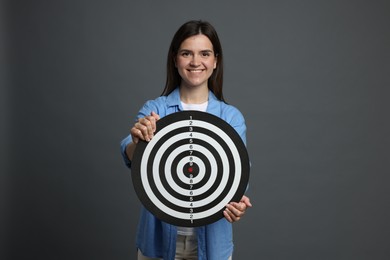 Photo of Targeting. Smiling woman with dart board on grey background