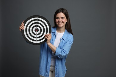 Photo of Targeting. Smiling woman with dart board on grey background
