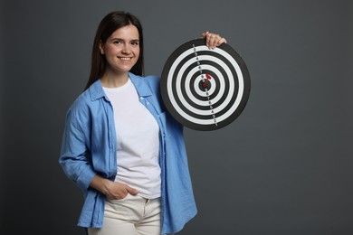 Photo of Targeting. Smiling woman with dart board on grey background