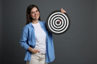 Photo of Targeting. Smiling woman with dart board on grey background