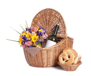 Photo of Picnic wicker basket with beautiful flowers, bottle of wine and pretzels isolated on white
