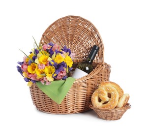 Photo of Picnic wicker basket with beautiful flowers, bottle of wine and pretzels isolated on white