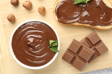 Photo of Tasty chocolate spread, toast, hazelnuts and mint on table, top view
