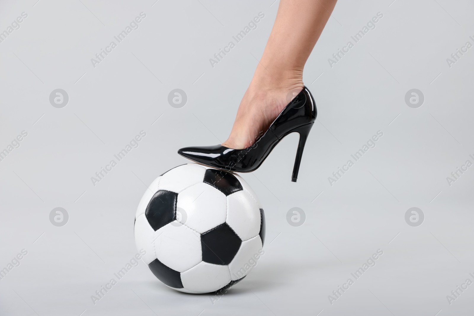 Woman in high heeled shoe with soccer ball on light background, closeup Photo of Woman in high heeled shoe with soccer ball on light background, closeup