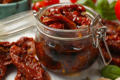 Photo of Delicious sun dried tomatoes in glass jar on table, closeup