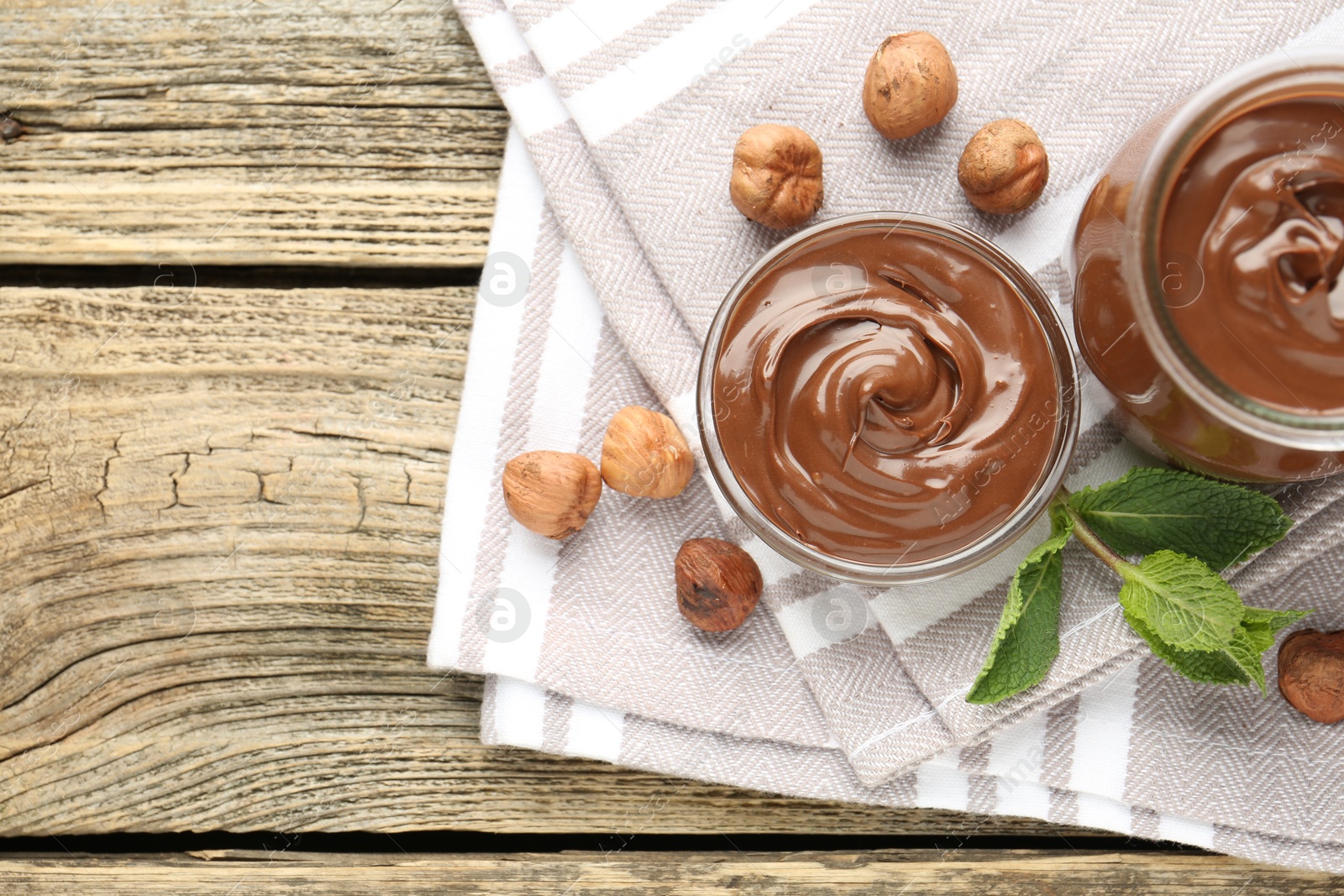 Tasty chocolate spread, hazelnuts and mint on wooden table, top view. Space for text Photo of Tasty chocolate spread, hazelnuts and mint on wooden table, top view. Space for text