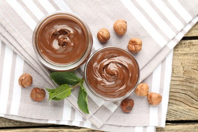 Photo of Tasty chocolate spread, hazelnuts and mint on wooden table, top view