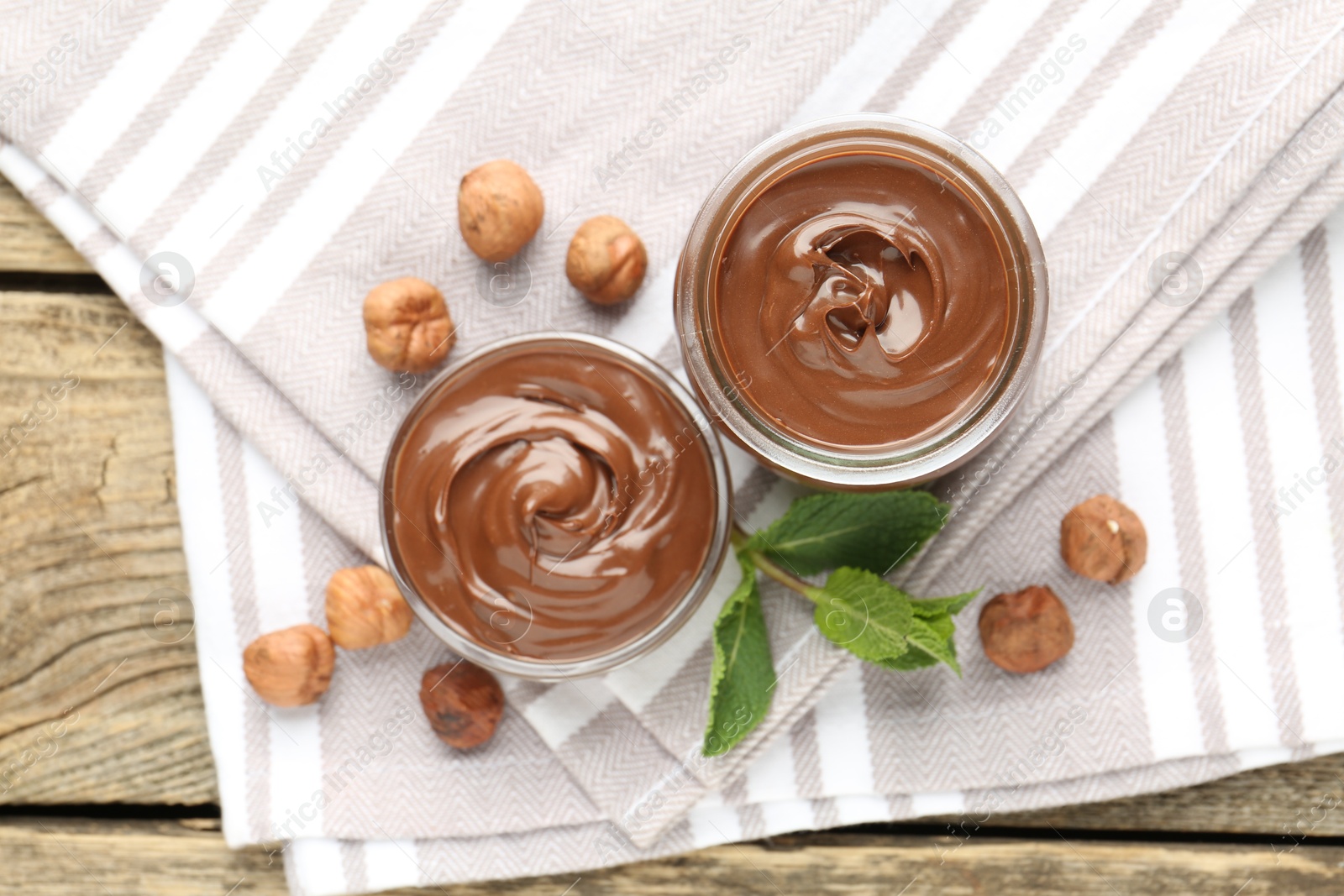 Tasty chocolate spread, hazelnuts and mint on wooden table, top view Photo of Tasty chocolate spread, hazelnuts and mint on wooden table, top view