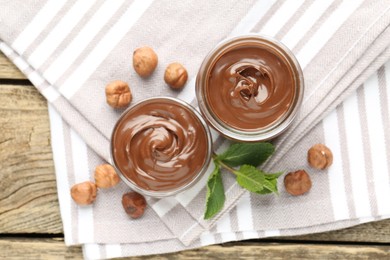 Photo of Tasty chocolate spread, hazelnuts and mint on wooden table, top view