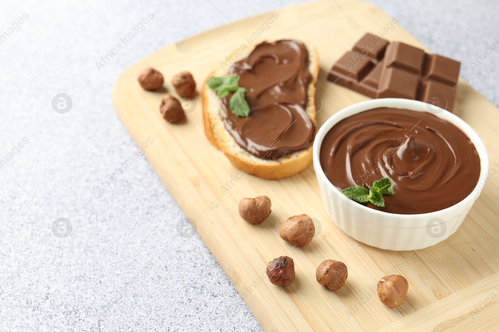 Tasty chocolate spread, toast, hazelnuts and mint on grey textured table, closeup. Space for text Photo of Tasty chocolate spread, toast, hazelnuts and mint on grey textured table, closeup. Space for text