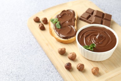 Photo of Tasty chocolate spread, toast, hazelnuts and mint on grey textured table, closeup. Space for text