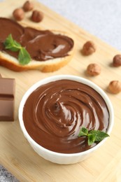 Photo of Tasty chocolate hazelnut spread with mint in bowl on grey table