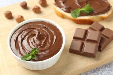 Photo of Tasty chocolate hazelnut spread with mint in bowl on table, closeup