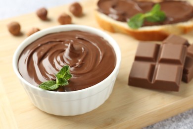 Photo of Tasty chocolate hazelnut spread with mint in bowl on table, closeup
