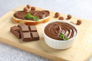 Photo of Tasty chocolate hazelnut spread with mint in bowl on grey textured table, closeup