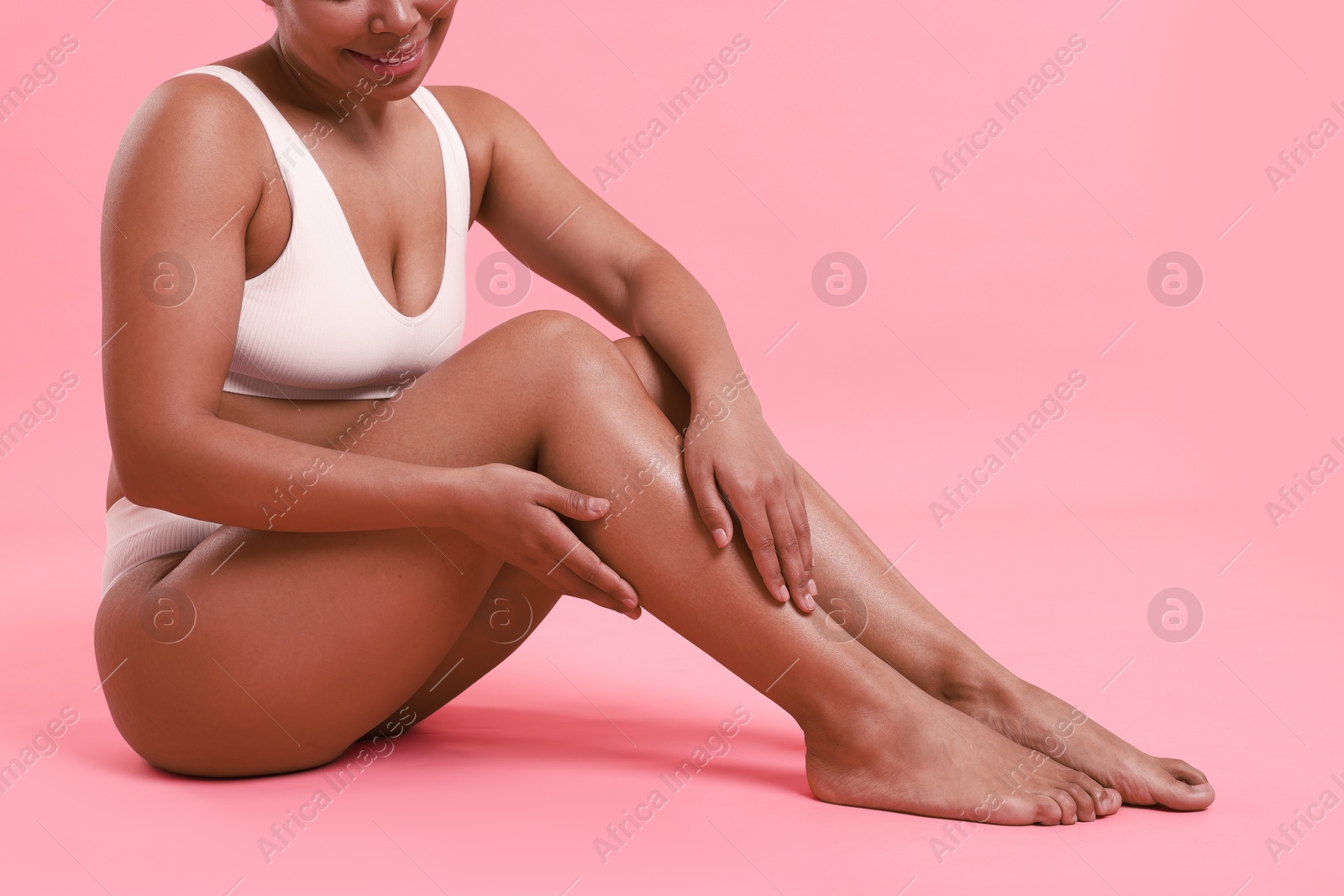 Woman in white underwear with smooth skin after epilation procedure on pink background, closeup Photo of Woman in white underwear with smooth skin after epilation procedure on pink background, closeup