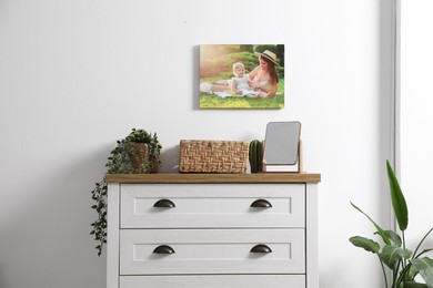 Photo of Dresser with stylish decor and houseplants near white wall indoors