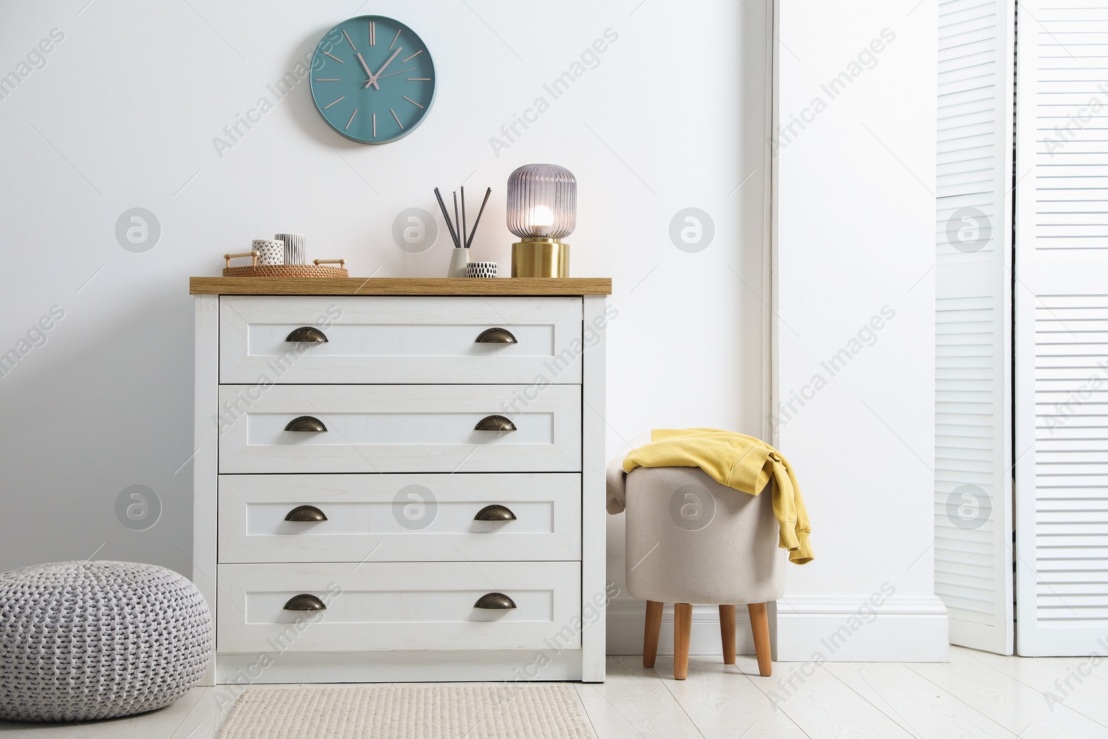 Dresser with stylish reed diffuser and lamp near white wall indoors Photo of Dresser with stylish reed diffuser and lamp near white wall indoors