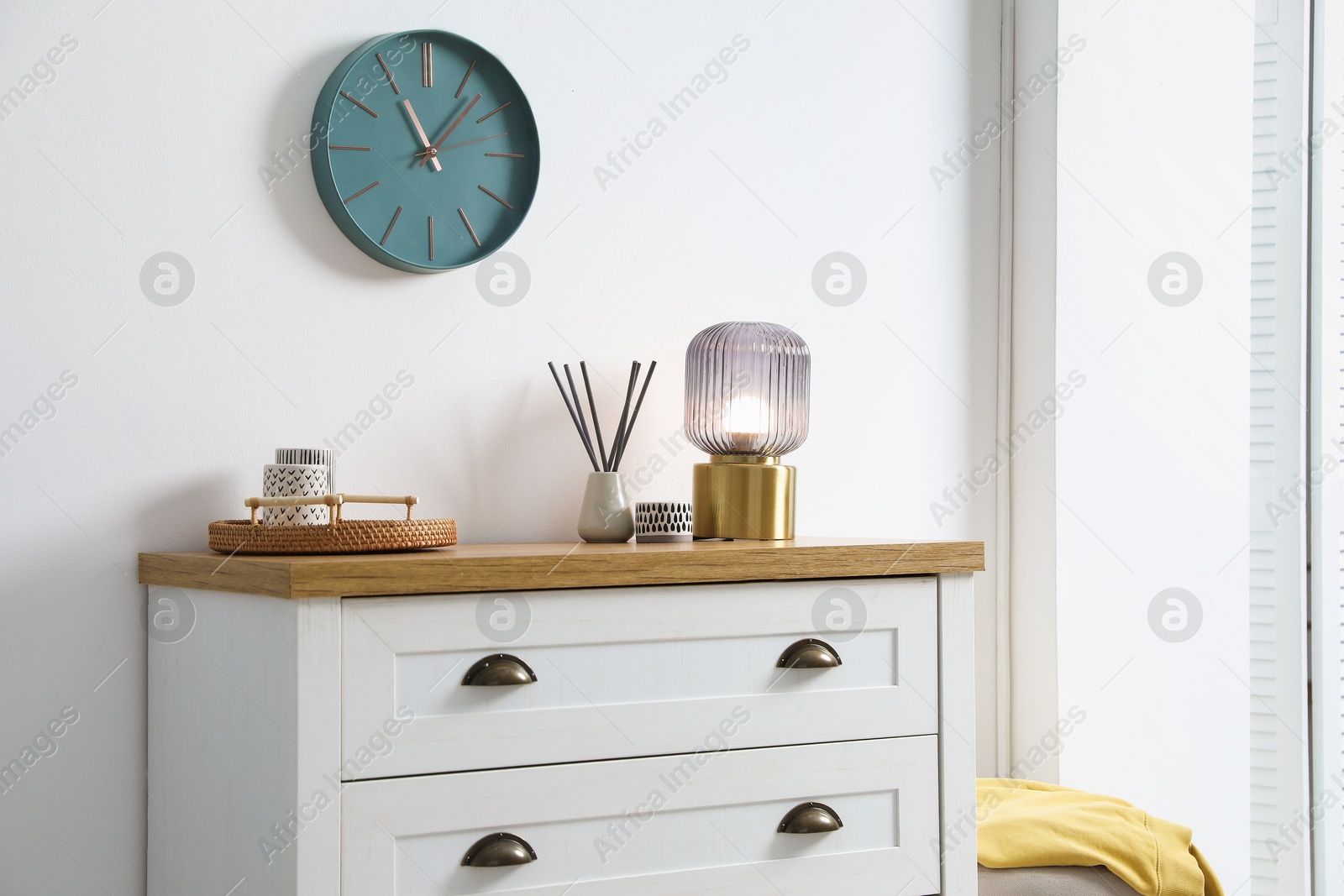 Dresser with stylish reed diffuser and lamp near white wall indoors Photo of Dresser with stylish reed diffuser and lamp near white wall indoors