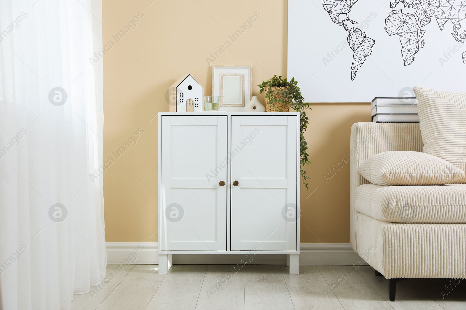 Photo of Dresser with stylish decor and houseplant near beige wall indoors