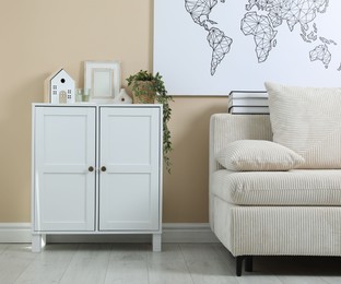 Photo of Dresser with stylish decor and houseplant near beige wall indoors