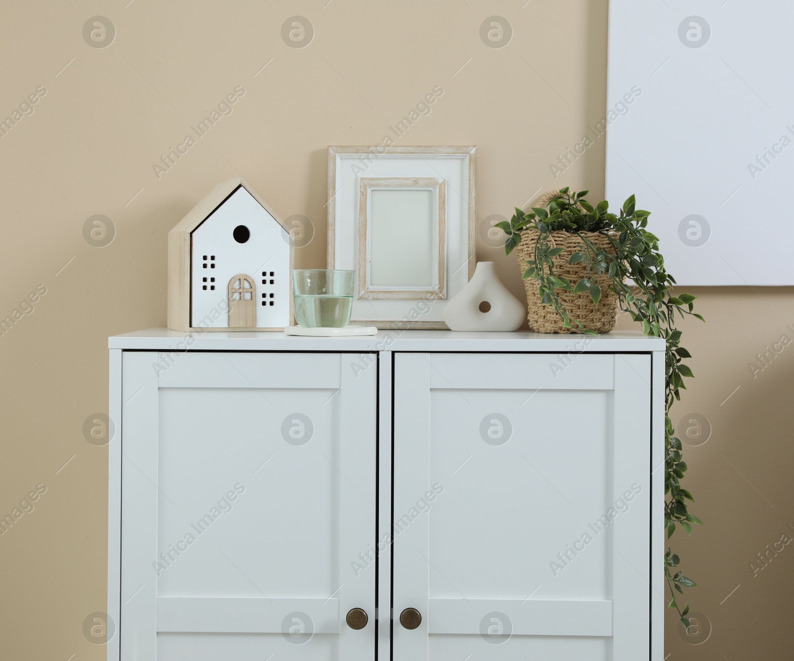 Dresser with stylish decor and houseplant near beige wall indoors Photo of Dresser with stylish decor and houseplant near beige wall indoors