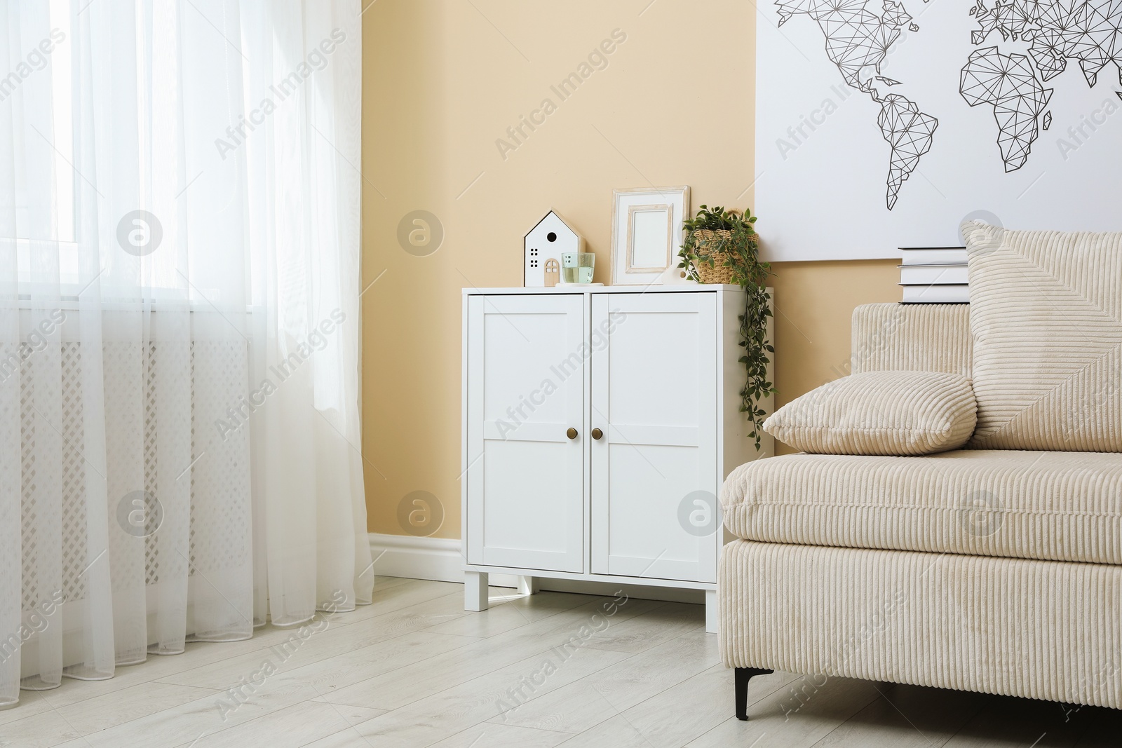 Dresser with stylish decor and houseplant near beige wall in room Photo of Dresser with stylish decor and houseplant near beige wall in room