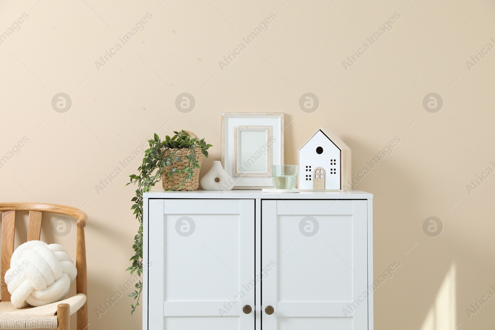 Dresser with stylish decor and houseplant near beige wall indoors Photo of Dresser with stylish decor and houseplant near beige wall indoors