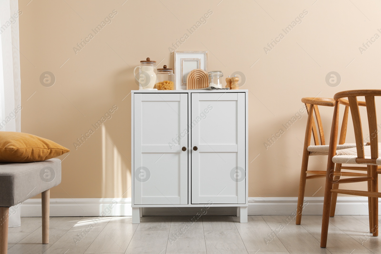 Dresser with stylish decor near beige wall indoors Photo of Dresser with stylish decor near beige wall indoors