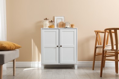 Photo of Dresser with stylish decor near beige wall indoors