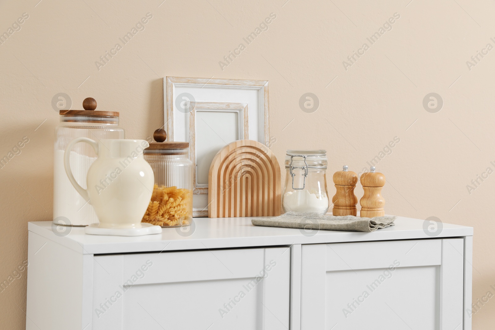 Dresser with stylish decor near beige wall indoors Photo of Dresser with stylish decor near beige wall indoors