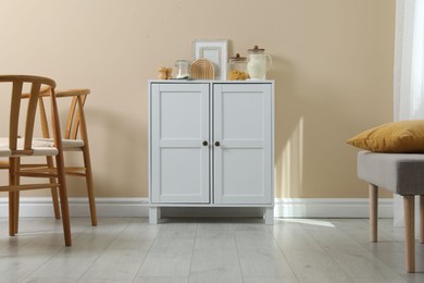 Photo of Dresser with stylish decor near beige wall indoors