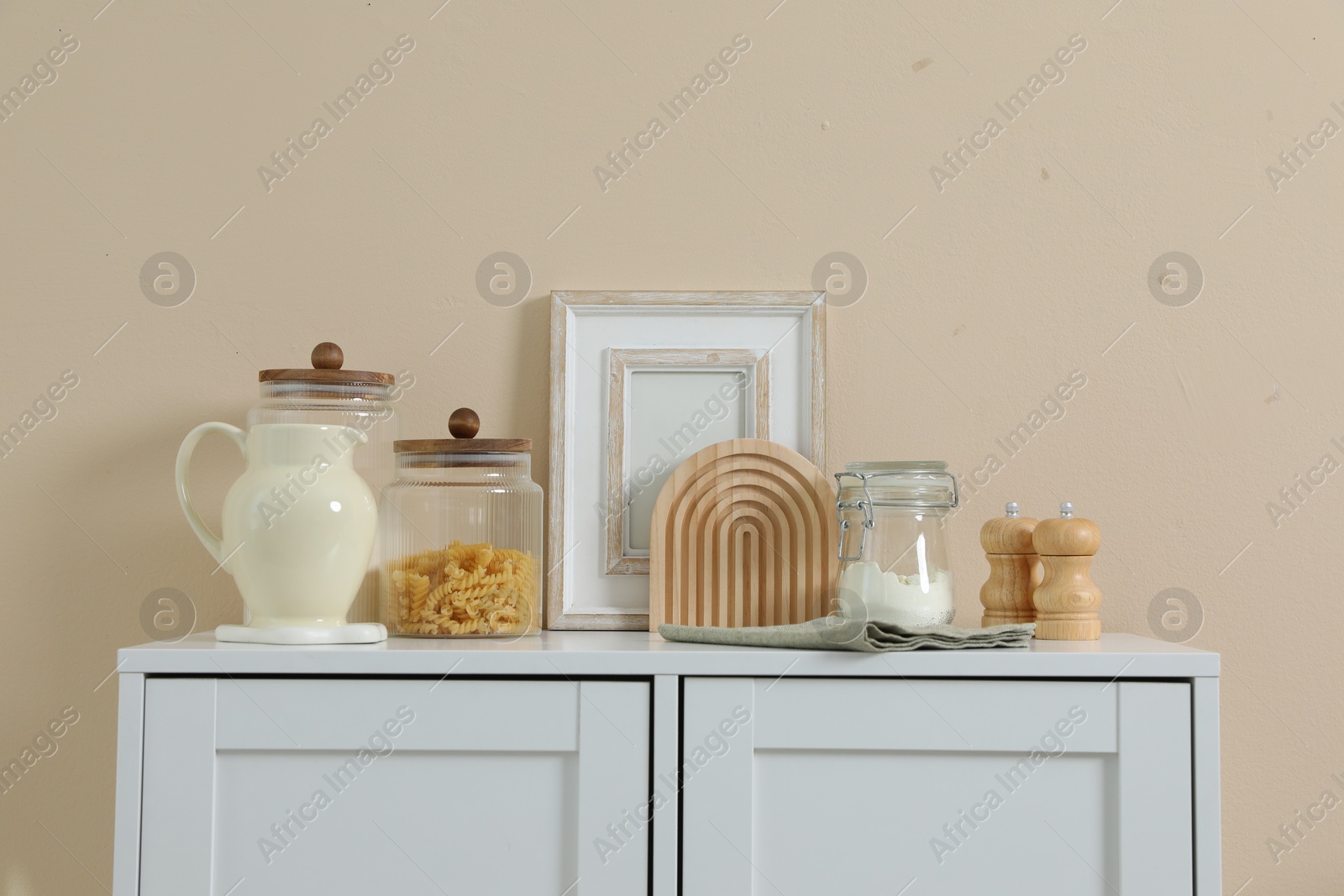 Dresser with stylish decor near beige wall indoors Photo of Dresser with stylish decor near beige wall indoors