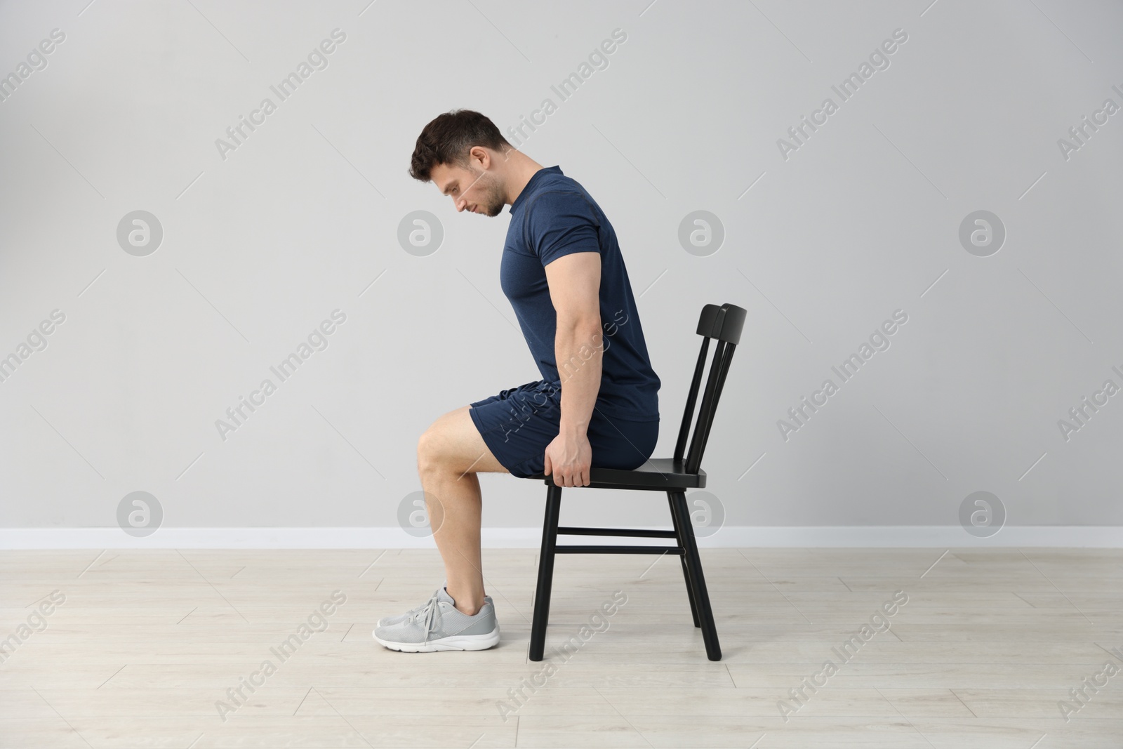 Handsome man exercising with chair at home Photo of Handsome man exercising with chair at home