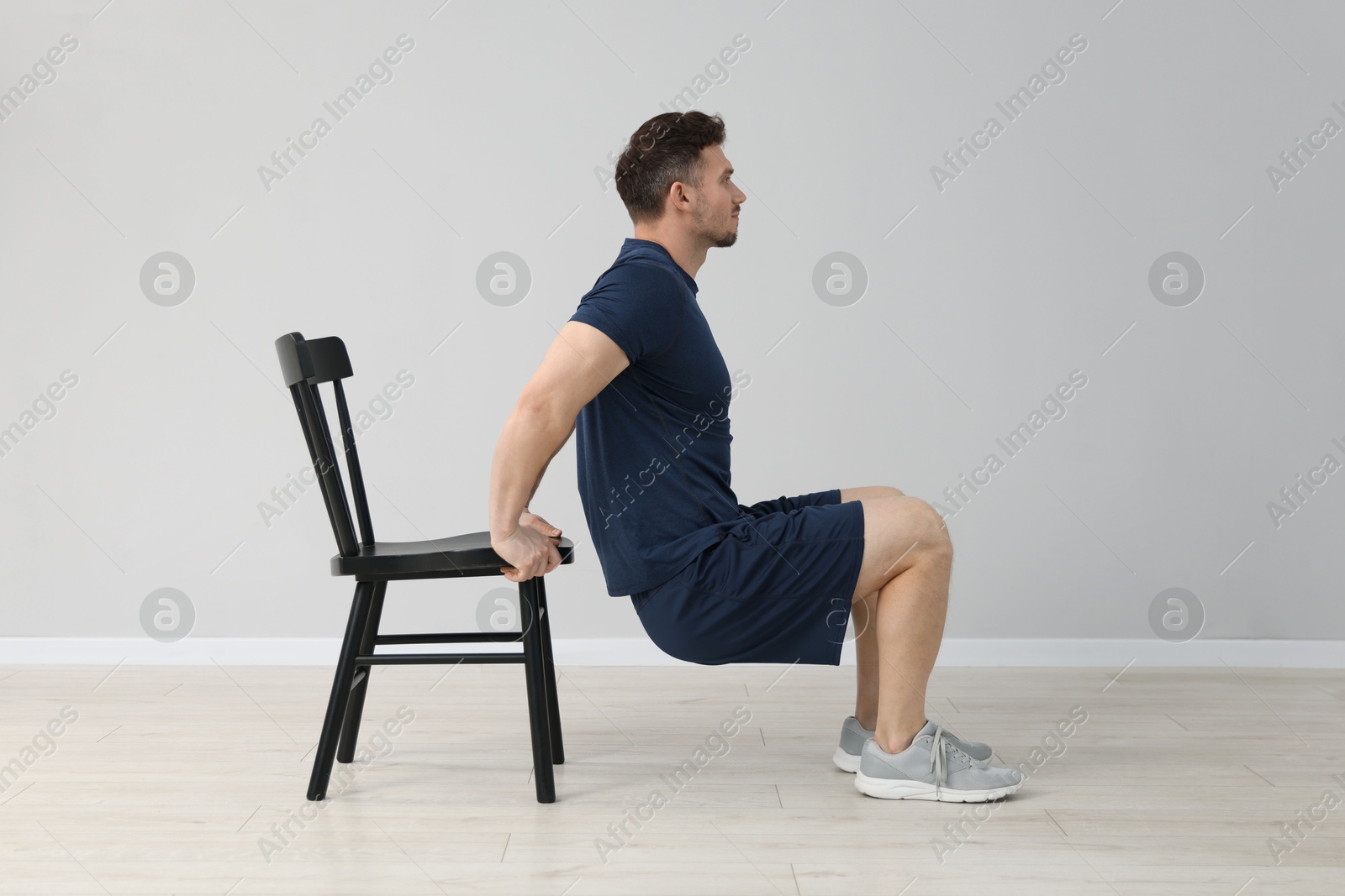 Handsome man exercising with chair at home Photo of Handsome man exercising with chair at home