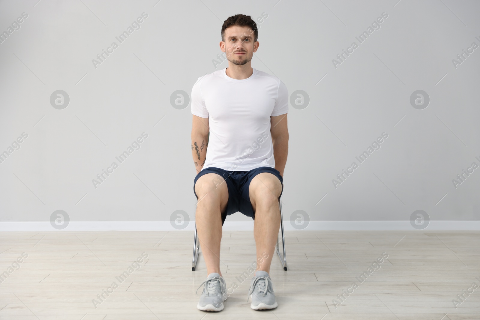 Handsome man exercising with chair at home Photo of Handsome man exercising with chair at home