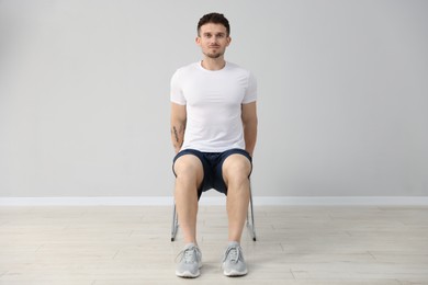 Photo of Handsome man exercising with chair at home