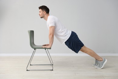 Photo of Handsome man exercising with chair at home