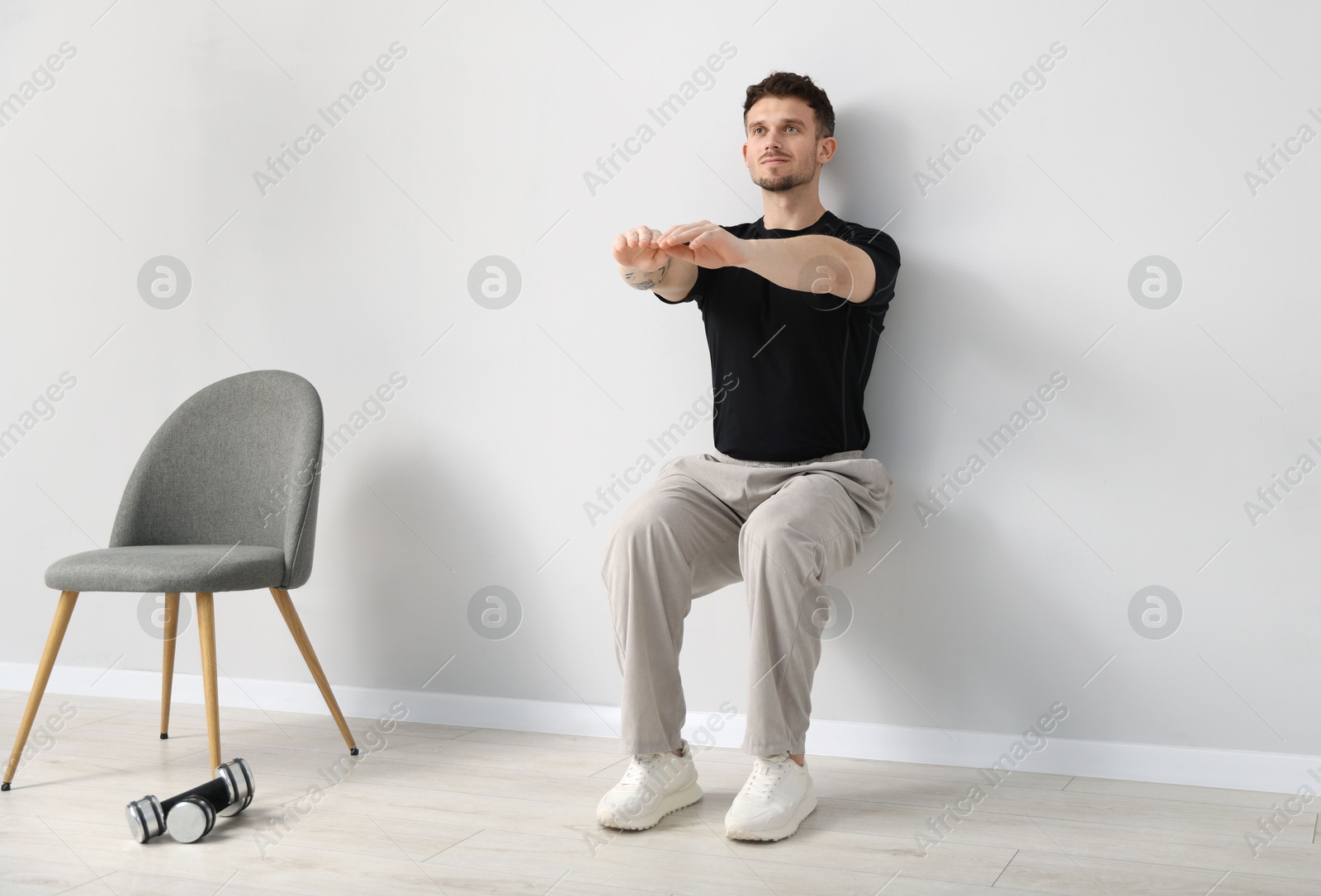 Handsome man exercising near light grey wall indoors Photo of Handsome man exercising near light grey wall indoors