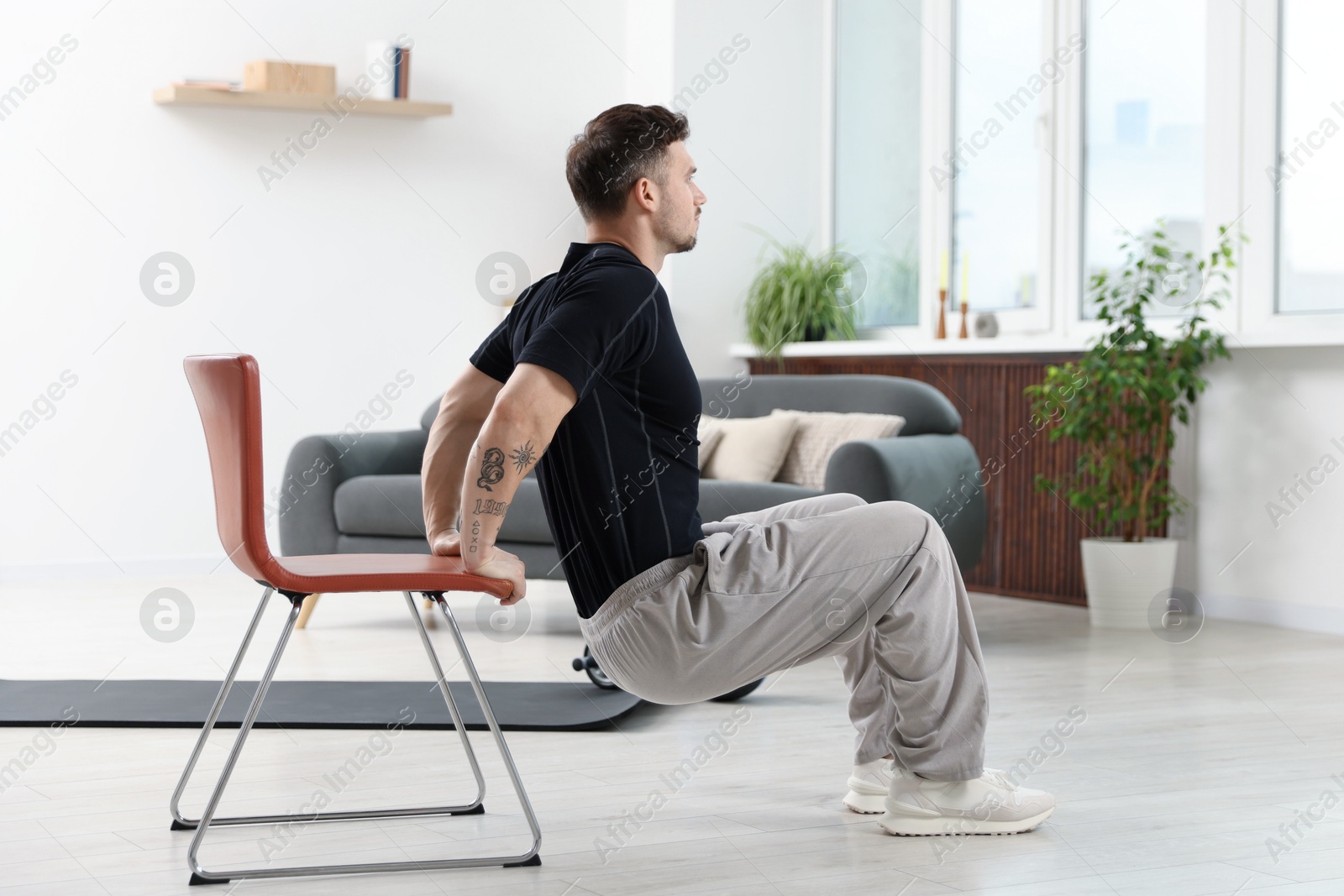 Handsome man exercising with chair at home Photo of Handsome man exercising with chair at home