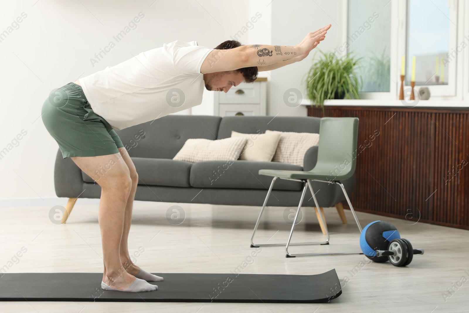 Handsome man exercising on fitness mat at home Photo of Handsome man exercising on fitness mat at home