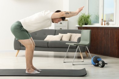 Photo of Handsome man exercising on fitness mat at home