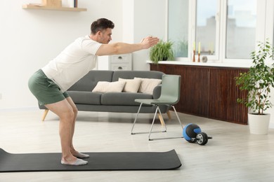 Photo of Handsome man exercising on fitness mat at home