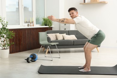 Photo of Handsome man exercising on fitness mat at home