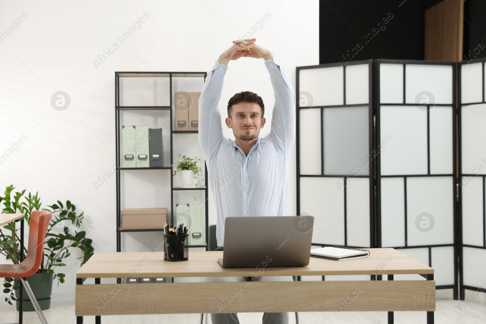 Handsome man stretching on chair in office Photo of Handsome man stretching on chair in office