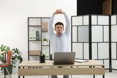 Photo of Handsome man stretching on chair in office