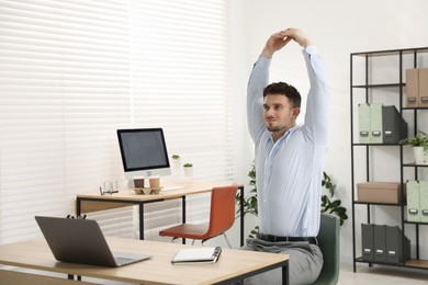 Photo of Handsome man stretching on chair in office